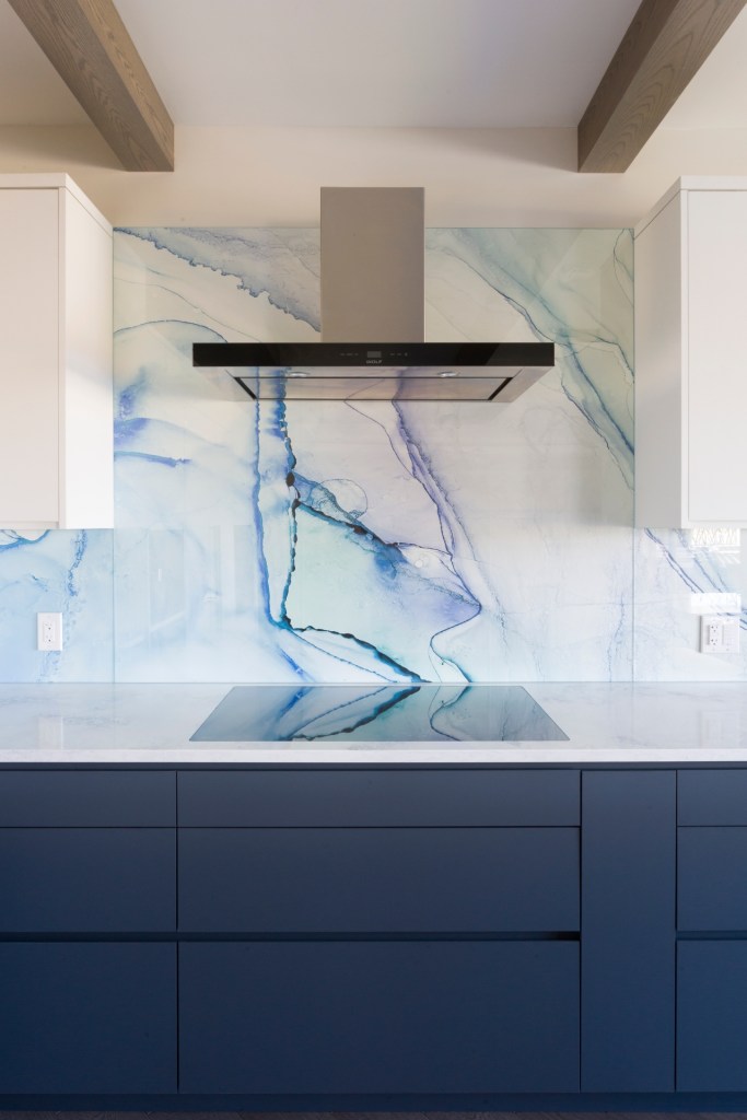 Painted kitchen cabinets with wallpaper backsplash set behind custom cut glass.